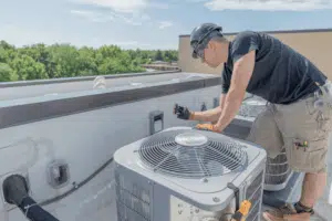 technician repairing commercial rooftop HVAC unit